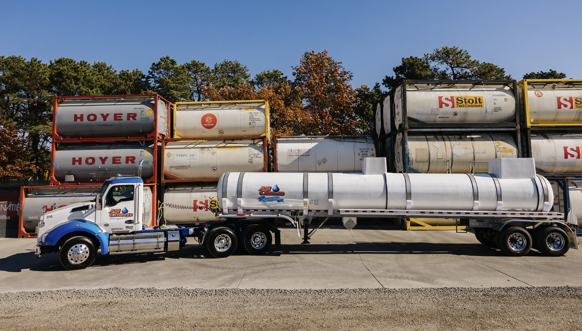 all-chem-truck-with-hazmat-tanker-driving-past-iso-containers